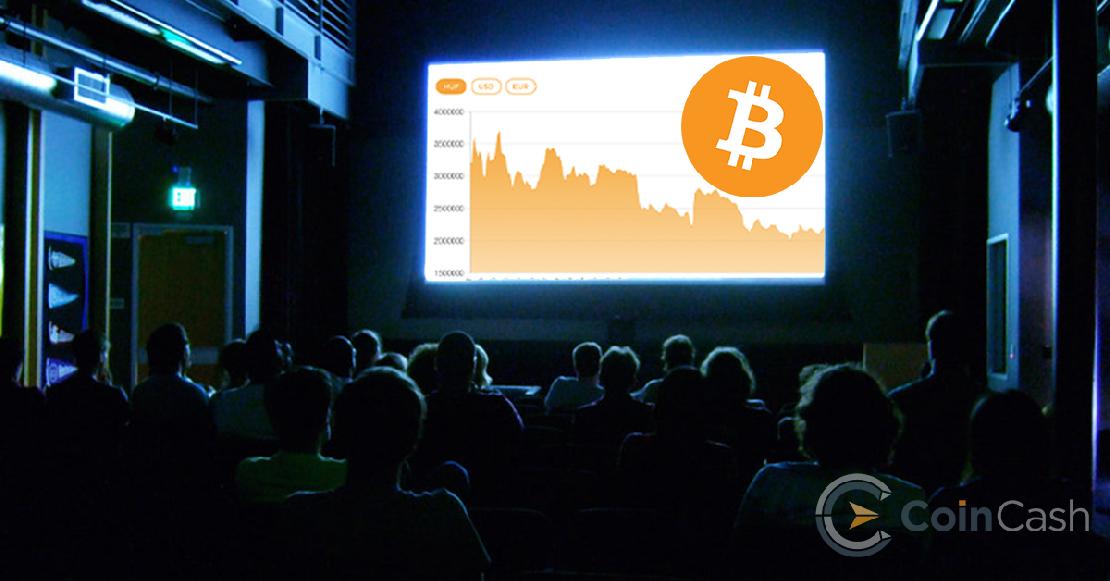 Moziban ülő közönség nézi a vásznat, amin a bitcoin árfolyam látható. 