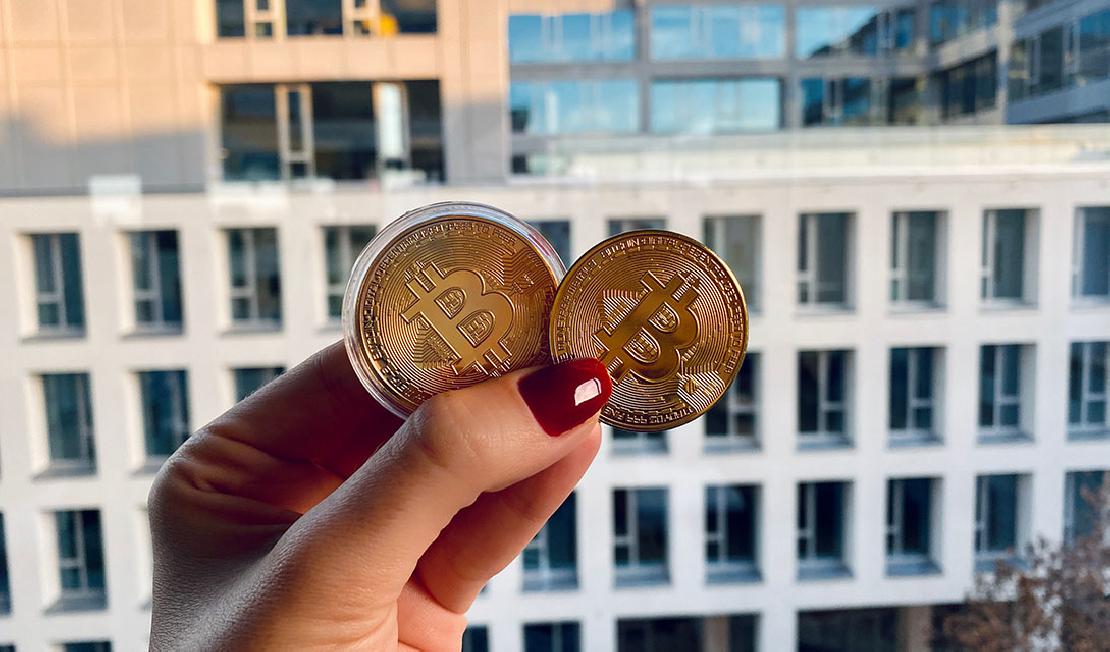 Két bitcoin jeles érme egy női kézben. 