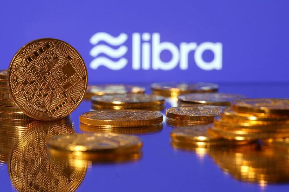 Bitcoin érmék, a háttében kissé homályosan a facebook libra logója. 