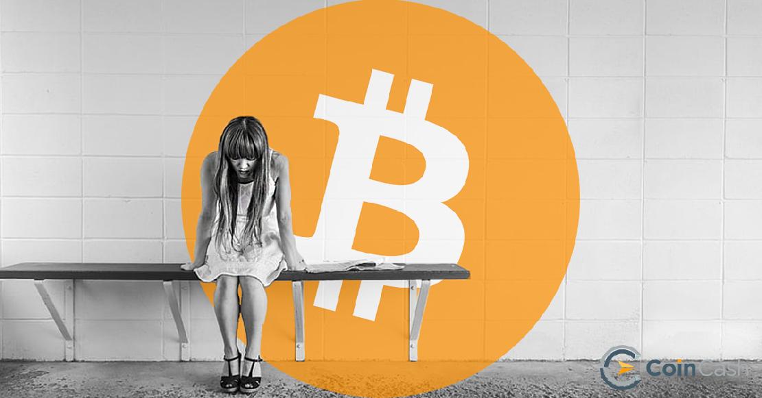 Egy lány szomorúan ül a padon, mögötte bitcoin logó látható.